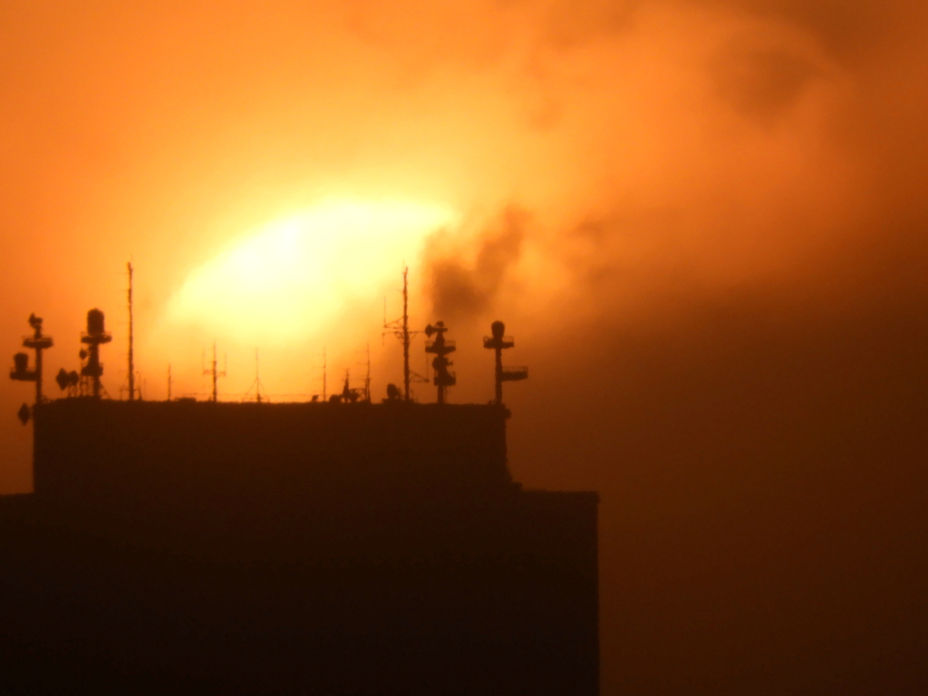 段々右にズレる大きな夕日が雲の下に入り込む
