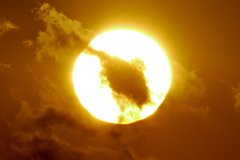 暮れの荒川土手から夕日の前を横切る遠くの雲