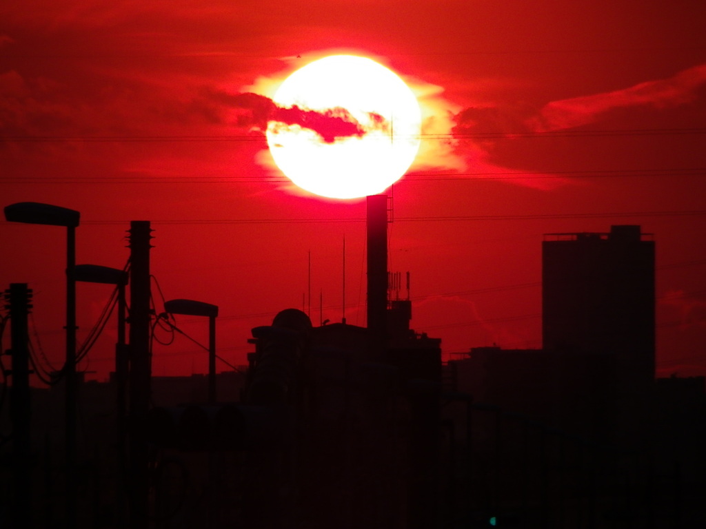 新川土手下の煙突に接触する夕日