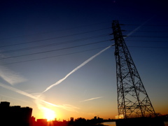 夕日から鉄塔の上に伸びる飛行機雲