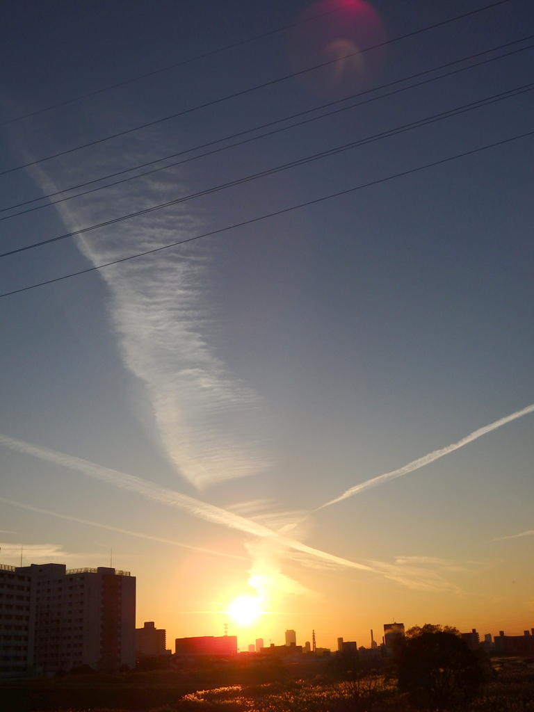 夕日から十字に伸びる飛行機雲