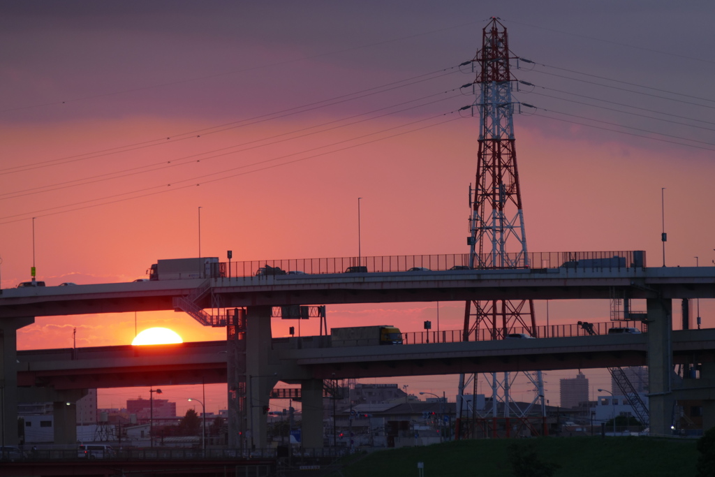 高速の後ろの雲に落ちる夕日