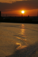 隅田川の夕日と船の波紋
