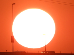 高速道路を走る車の上の大きな夕日