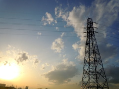 黄色い夕日と西新井橋の河原から建つ鉄塔の空の雲