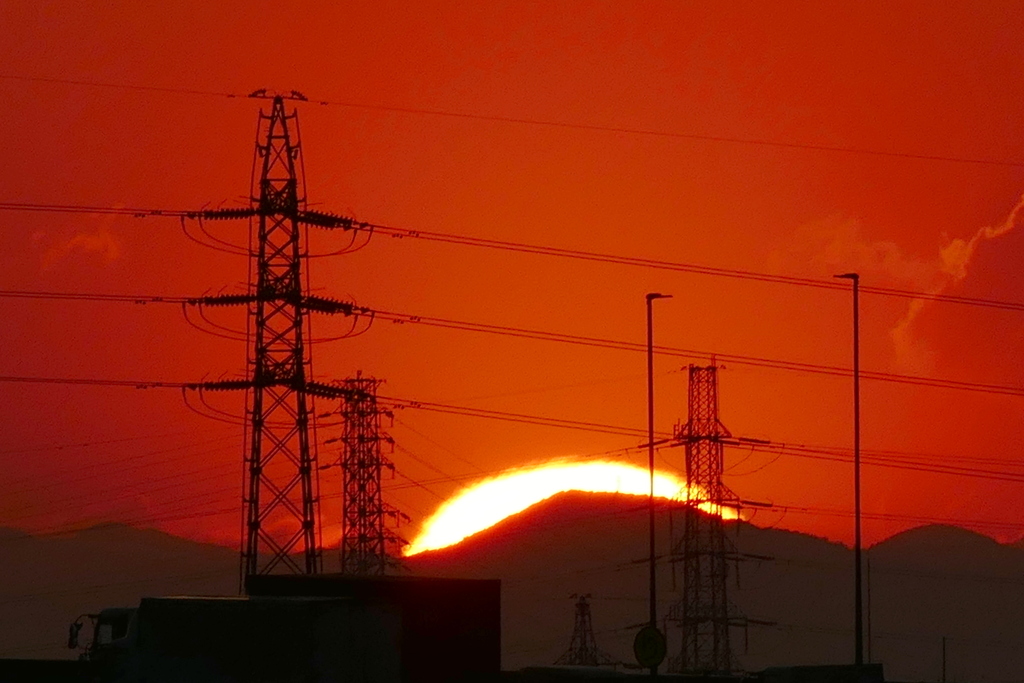 鉄塔の奥の丸山に沈む