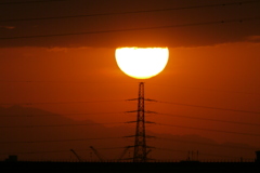 雲から再び出現する鉄塔の上の夕日