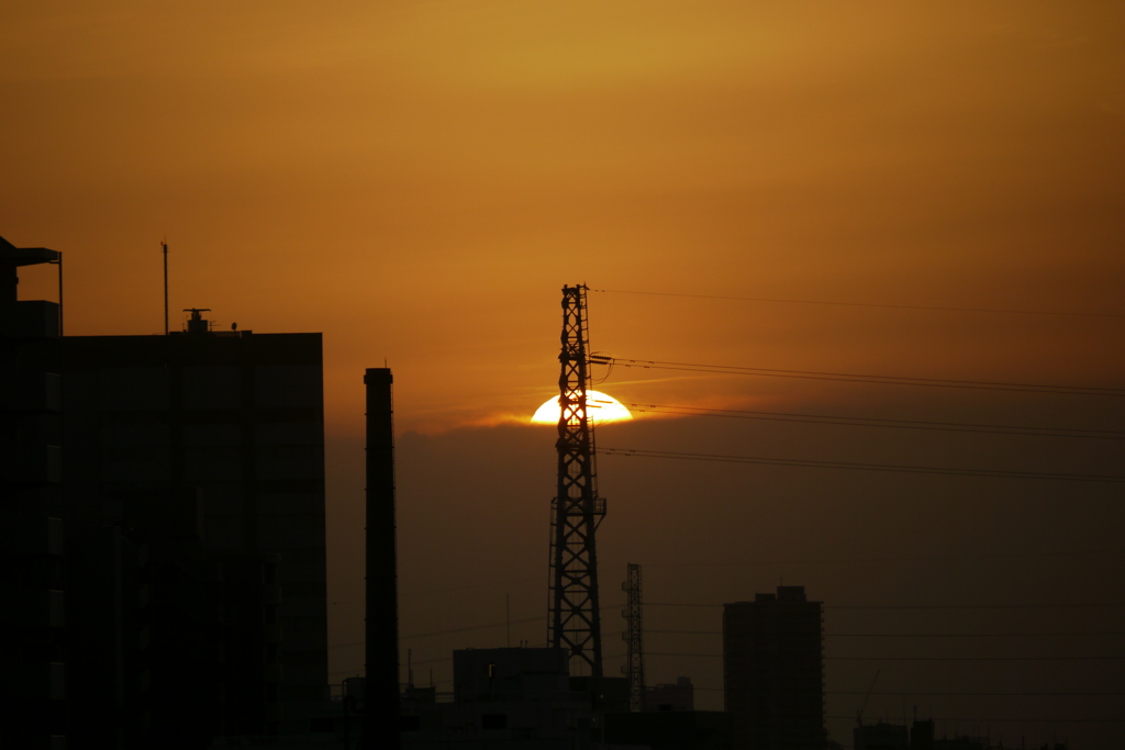 鉄塔後ろの黒雲に沈む夕日
