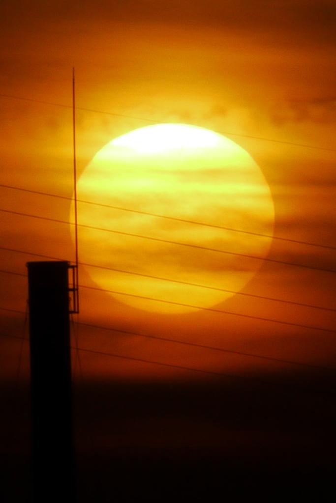 隅田川の煙突と並ぶ大きな雲被る夕日