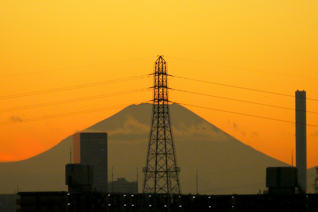 鉄塔の後ろの山下に雲がある富士山