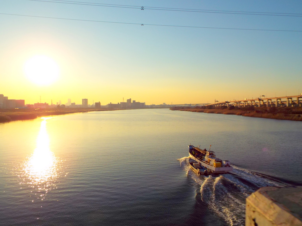 西新井橋から黄色い夕日の川を上る船