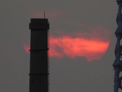 隅田川の煙突の後ろの雲間に消える夕日