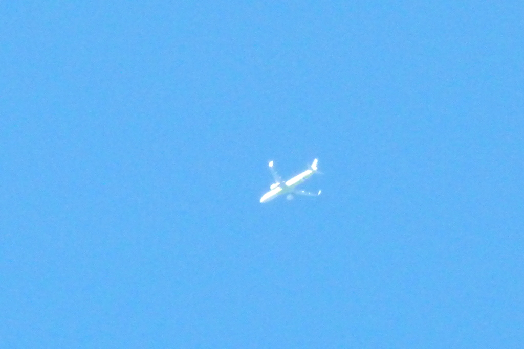 快晴の空を高く飛ぶ飛行機