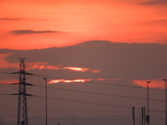 千住新橋から鉄塔右下の堂平山の背後の黒雲の中に沈む夕日
