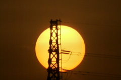 鉄塔の後ろの大きな夕日