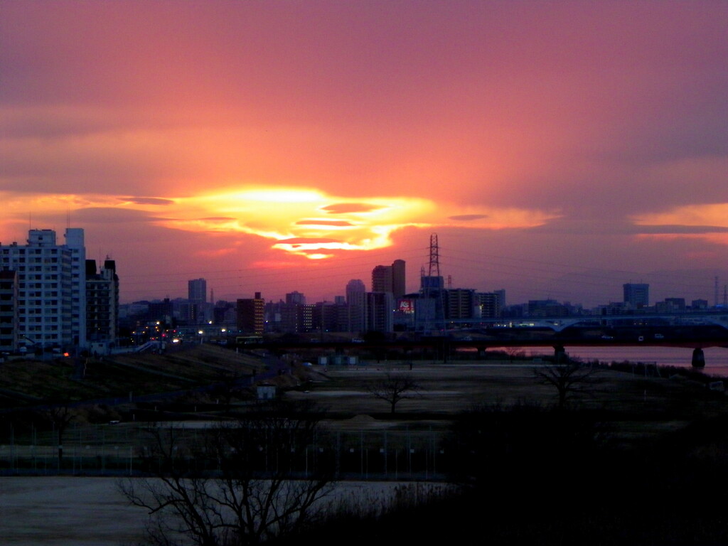 千住新橋から雲の後ろの夕日のオレンジ色の放射光が