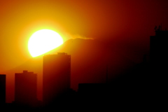 サンシャインビル上の富士山の山腹に隠れる黄色い夕日