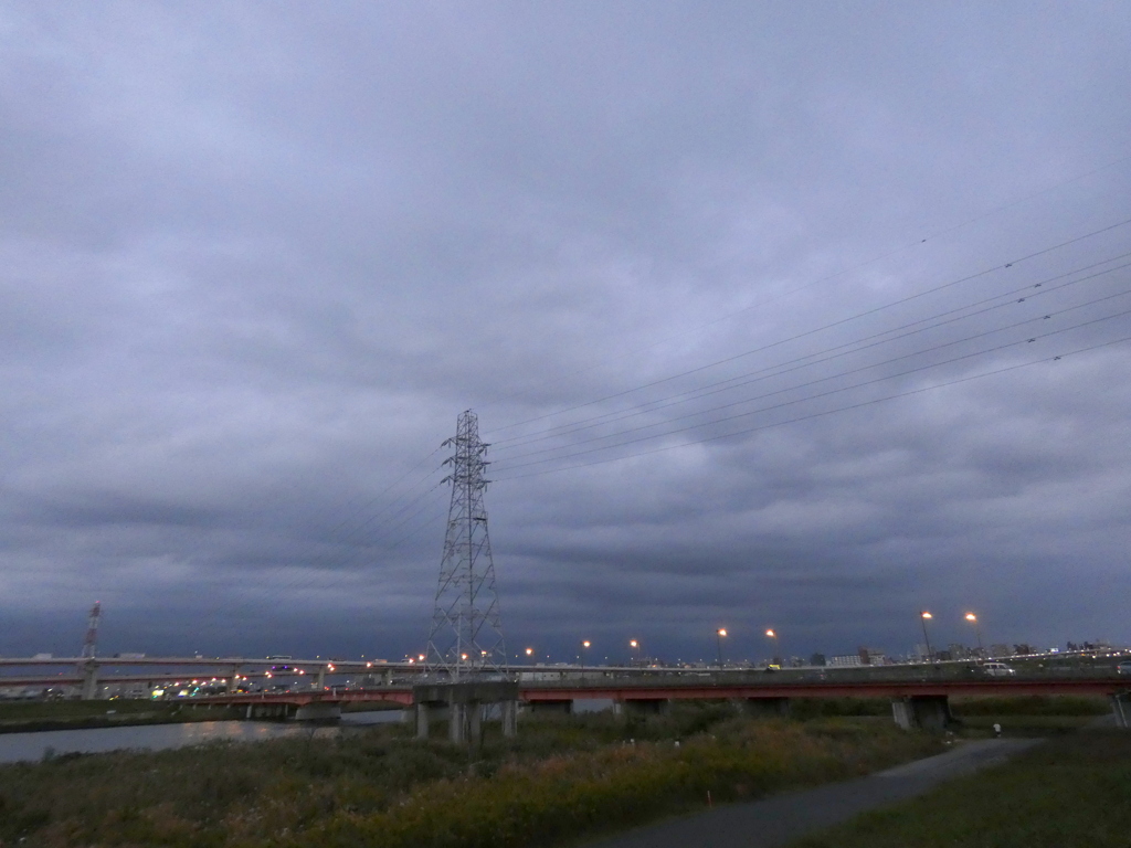 荒川の西新井橋上のグレーの鉄塔と雲