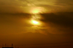 黒雲被る薄赤の夕日