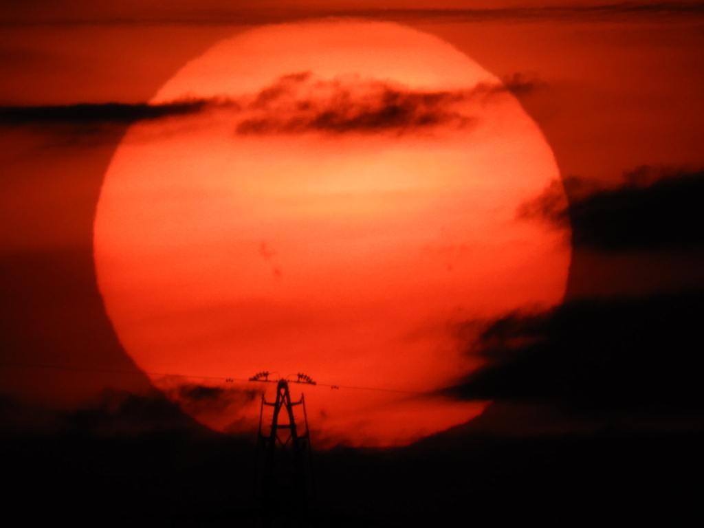 鉄塔の周りの雲間の夕日