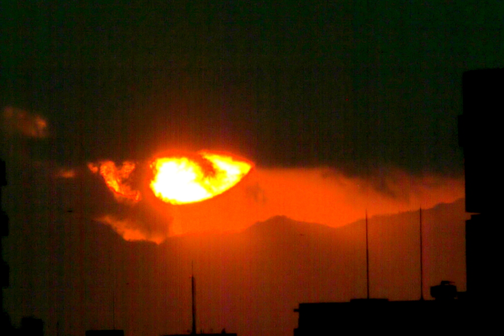 暮れの荒川土手から丹沢山系の上空の雲から顔を出す東京タワー上空の夕日