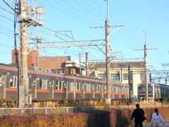 千住大橋の踏切の交差する夕日の京成線