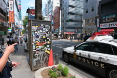 渋谷の電話ボックスとパトカーと警察官の腕