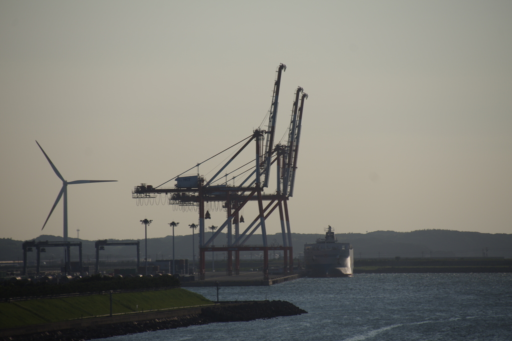 クレーンと貨物船と風力発電