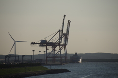 クレーンと貨物船と風力発電