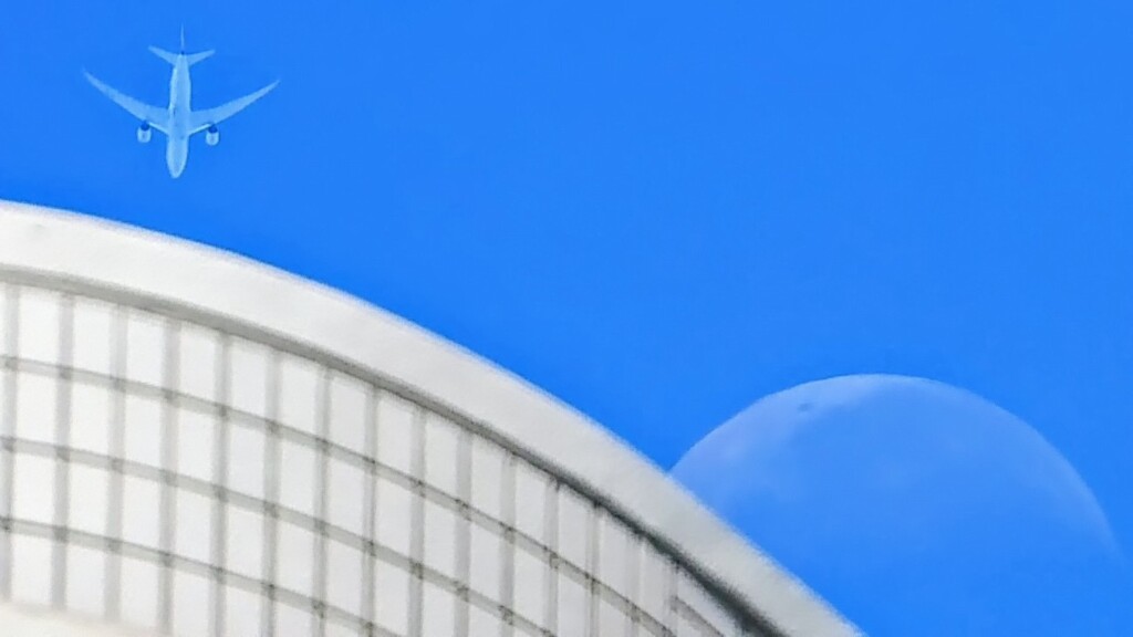 マンションと下弦の月と旅客機。
