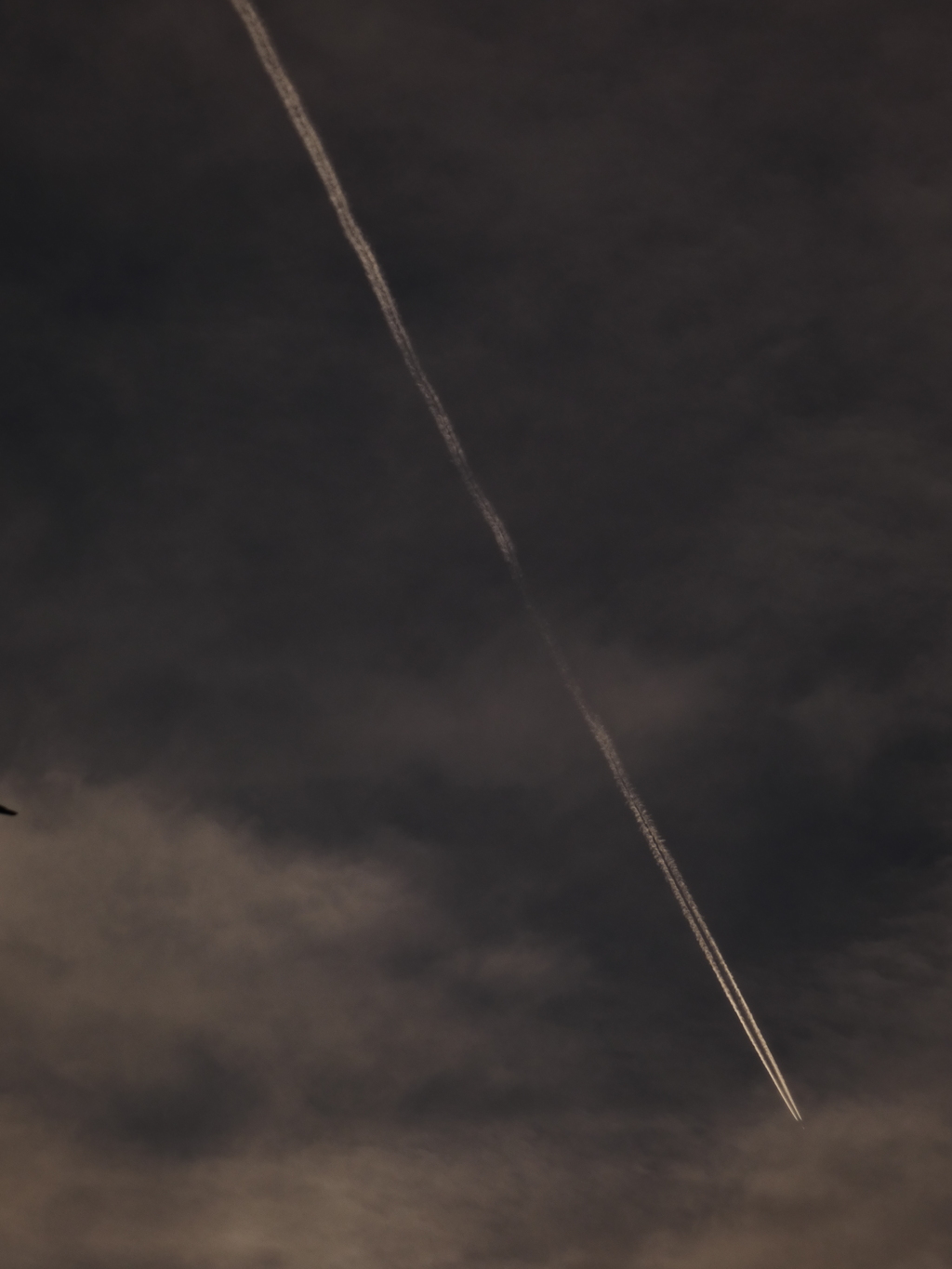 雪雲下の飛行機雲