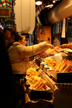 錦市場で天ぷらを買う女性