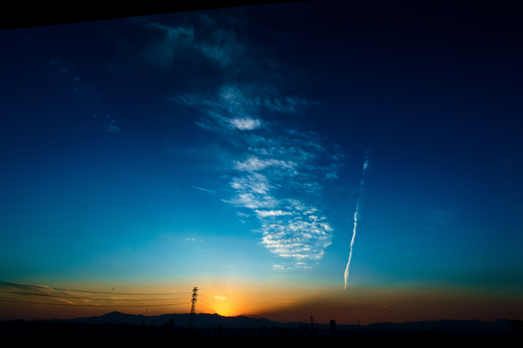 落ち行く夕陽と飛行機雲