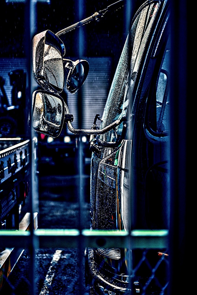 柵の向こうのトラックのミラー