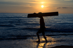 流木を担ぐ少年