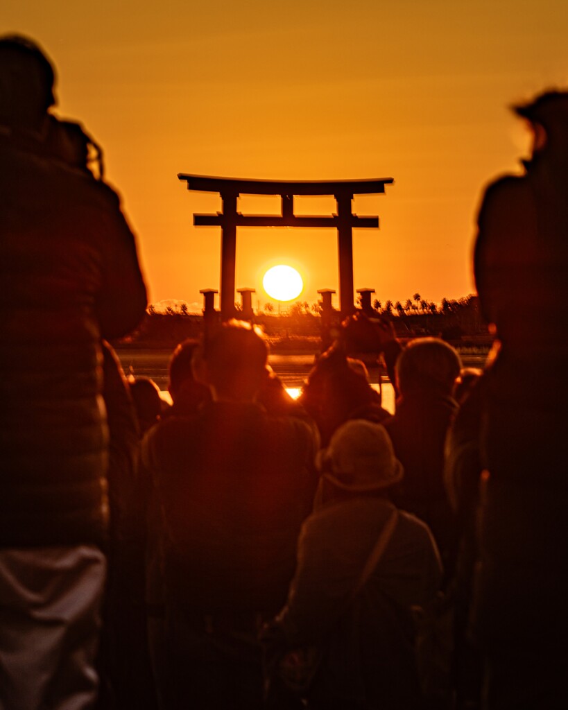 鳥居に沈む夕日と観衆