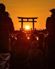 鳥居に沈む夕日と観衆