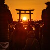 鳥居に沈む夕日と観衆