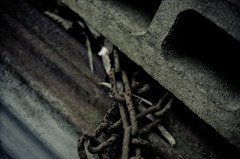 錆びたトタンの上の錆びた鎖を下敷きにするブロック