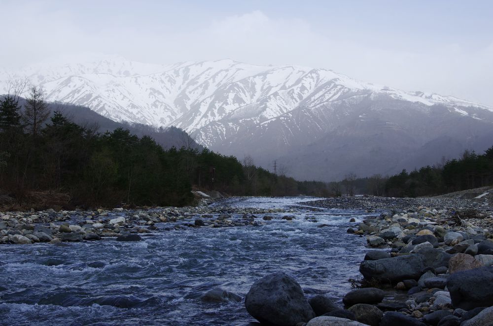 雪融けの高瀬川と春霞の北アルプス（蓮華岳）