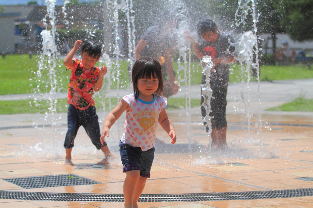 水で遊ぶ男の子、水から逃げる女の子。