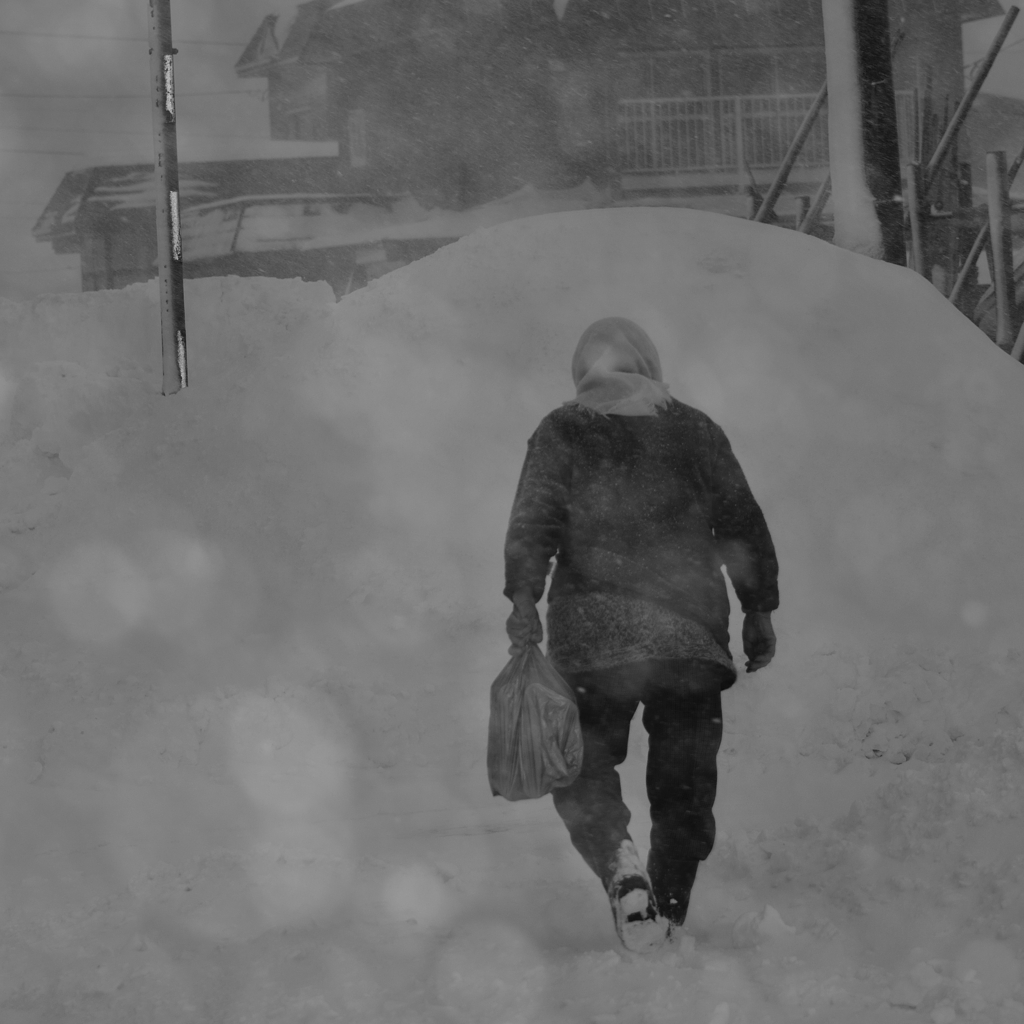 吹雪の中、買い物帰りの老婆
