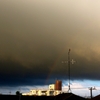 虹を呑み込む黄砂のような雨雲