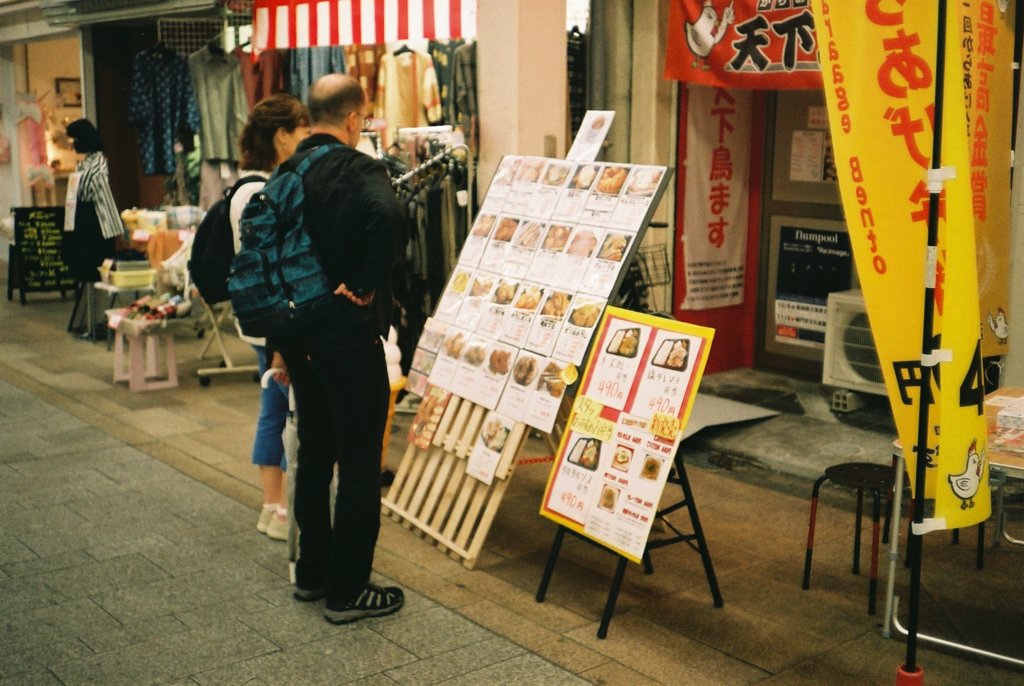 唐揚げ屋の前で立ち止まる外国人観光客