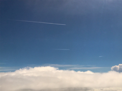 飛行機行き交う雲上の青空
