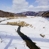 雪原を流れる川と橋梁の影
