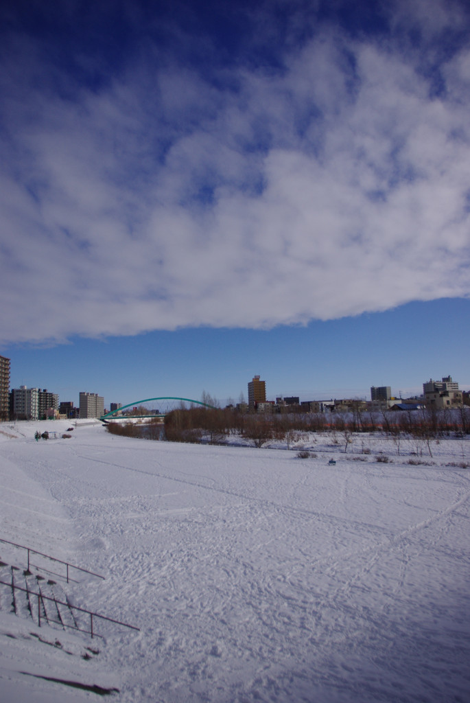 雪の河原に雲と青空