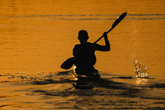 Man paddling a kayak in the morning sun