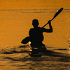 Man paddling a kayak in the morning sun