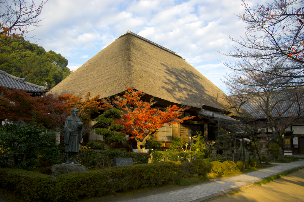 朝日を浴びるかやぶきと紅葉